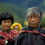 Grandmother and mother wearing bright headscarves tenderly hold and observe newborn baby