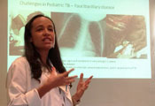 Haitian researcher Dr. Vanessa Rouzier speaks, slide on challenges in pediatric TB projected in background