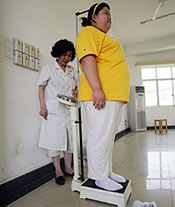 A child is being weighed by a medical worker at a base of the Aimin Slimming Centre in Wuhan of Hubei Province, China.