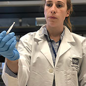 NIH investigator works in lab, holds swab tester.