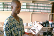 Healthcare worker examines large package of drugs, pharmaceutical shelves with similar packages, pill bottles in background