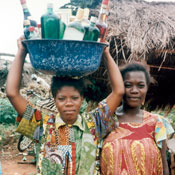 � 1996 Sara A. Holtz, Courtesy of Photoshare, 2 African women outdoors, one balances tub full of alcohol bottles on her head