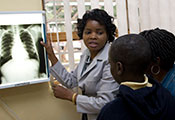 Photo by Richard Lord for Fogarty/NIH, Medical worker points to chest x-ray on lightbox while speaking with a boy and adult
