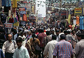 © 2003 Vijay Sureshkumar, Courtesy of Photoshare. City street very crowded with pedestrians, tall buildings with signs and merchandise line the street.