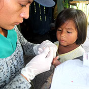 Medical worker administers fingerstick blood test on young girl in Peru