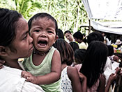 © 2012 Jundio Salvador, Courtesy of Photoshare. Crying child held while waiting in long line outdoors in the Philippines.