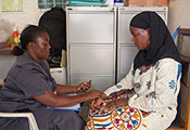 Photo by Richard Lord for Fogarty/NIH. A medical worker takes the pulse of a patient in a clinic.