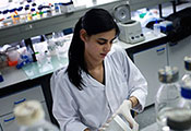 female researcher works in lab wearing white lab coat