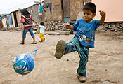 A young boy plays soccer in a neighborhood street in Peru