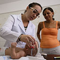 In Brazil, in a clinic, medical worker measures a baby's head circumference while mother looks on