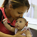 In Brazil, a mother kisses baby, who has a smaller than usual head