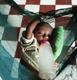 Photo of a child with a bottle sleeping in a net hammock