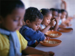 Photo: Children sit at a long table eating from bowls