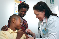 Young boy receives a vaccination shot in his arm from a nurse