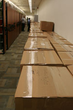 Photo: a long line of packed and sealed boxes next to library stacks