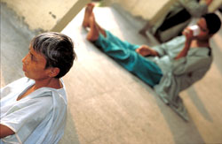 PHOTO: A man up close seated on the floor stares off camera; one in the background, out of focus, also seated on the floor