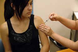 A young woman receives a shot in the arm.