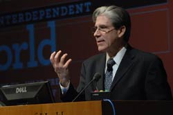 PHOTO: Dr. Julio Frenk speaks at a podium, gesturing with hands, unreadable slide in background