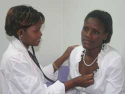 Photo: Dr Moses uses stethoscope to listen to a woman’s chest in an exam room