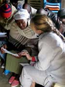Dr. Elizabeth Vaughan, facing away from camera and pointing at clipboard, interviews an African woman
