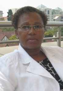 Close up of Dr. Emilia Noormahomed seated on balcony, rooftops in background