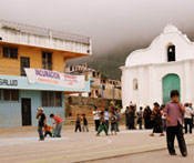 Children play on paved courtyard, buildings in background