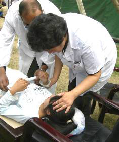 Dr. Ma Hong and a male doctor attend to a young girl on a gurney. Photo by Li Weihui.