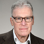 Photo portrait of Rob Eiss wearing glasses, a dark blazer, and a white shirt.
