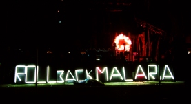 the words Roll Back Malaria in lights at a nighttime function