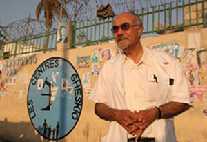 Dr. Bill Pape outside in Haiti with sign in background reading Les Centres GHESKIO