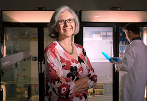 Dr. Michèle Ramsay stands in lab, worker in background