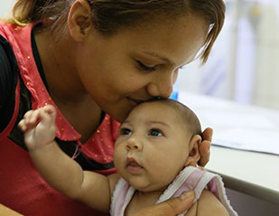 Photo by Harold Ruiz/PAHO-WHO, in Brazil, a mother kisses baby, who has a smaller than usual head