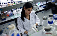 female researcher works in lab wearing white lab coat