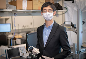 Photo courtesy of Worcester Polytechnic Institute. Dr. Haichong Zhang works with computer equipment in a lab wearing a mask.