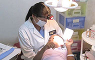 Dr Lilliam Pinzón performs a dental exam for a child in a reclined dental chair