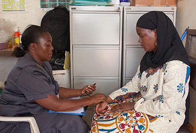 By Richard Lord for Fogarty/NIH. A medical worker takes the pulse of a patient in a clinic.