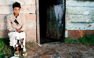 Photo by subman/iStock/Thinkstock. Xhosa woman in front of home in South Africa.