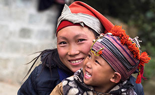 Young woman holds child in lap in Vietnam, both smiling