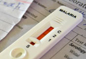 close up of white malaria test showing red indicator sitting on top of sheet of paper with title laboratory