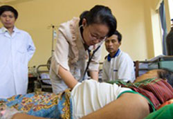 Doctors with a patient and her husband at a Cambodian AITRP hospital site.