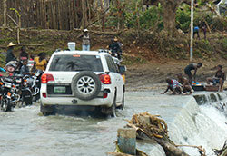 A CDC cholera investigation team crosses a river in a white SUV in Haiti after Hurricane Matthew in 2016.