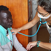 The photo shows Registered Nurse and Ph.D. Abigail Link treating a patient in Northern Uganda