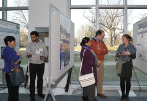 Hallway with scientific posters mounted on boards, researchers discuss their posters with conference attendees