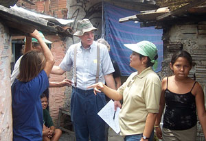 Dr. Richard Guerrant, center, speaks with team member and residents in a Brazilian shantytown next to run down buildings