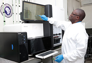 Dr. Christian Happi works in a lab on a large touch screen monitor.
