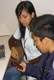 Seated next to each other, young man holds cell phone, female medical worker observes