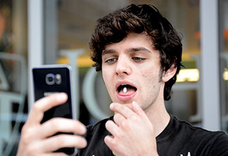 Man takes picture using a smartphone of himself taking a pill by mouth