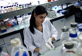 female researcher works in lab wearing white lab coat