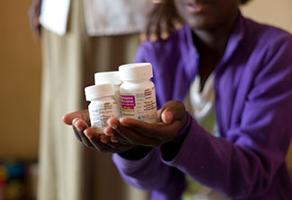 Hands of patient holding 3 bottles of atriretroviral medicines 