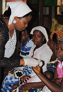 In Nigeria, woman tests an expectant mother for HIV, other expectant mothers in background